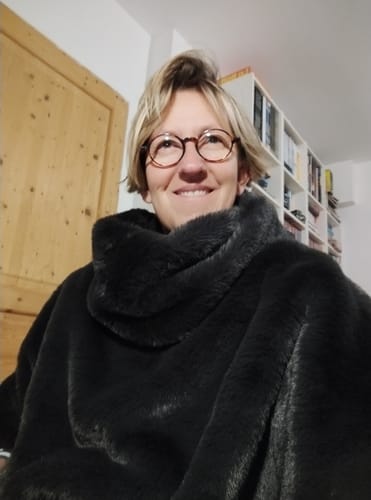 Cliente souriante portant le snood Douillet Nilo en fourrure cendrée douce et volumineuse.