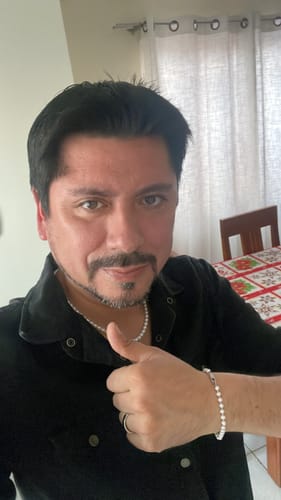 Un cliente muestra su Pulsera River Pearls y un collar a juego, haciendo un gesto de aprobación con el pulgar.