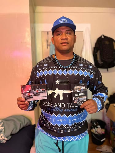 Customer in a patterned sweater and a blue cap, holding up two promotional cards.