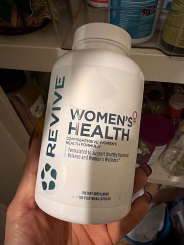 Reviewer holding a white bottle of Revive Women's Health supplement.