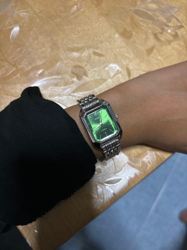 Customer wearing the silver CLAIRE DE MAINS watch on their wrist, showing off its vibrant green dial.
