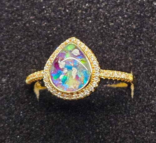 A reviewer's close-up of the Bedazzled Pear Opal Ring, showing its colorful stone and detailed gold band.