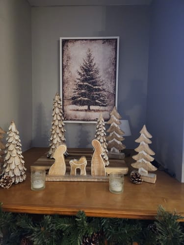 Reviewer's Vintage Pine Tree Christmas Wall Art displayed on a wall behind a lovely wooden manger scene.