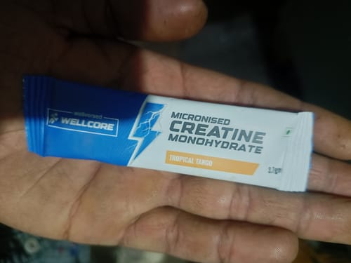 Customer holding a single sachet of Wellcore Micronised Creatine Monohydrate in Tropical Tango flavor.