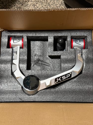 Customer's new silver KSP upper control arm resting in its packaging foam before installation.