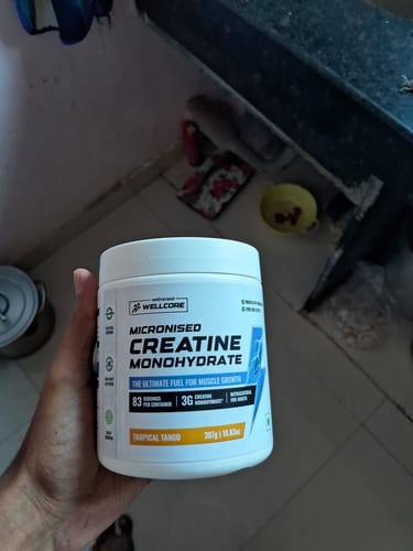 Customer holding the white container of Wellcore Micronised Creatine Monohydrate in Tropical Tango flavor.