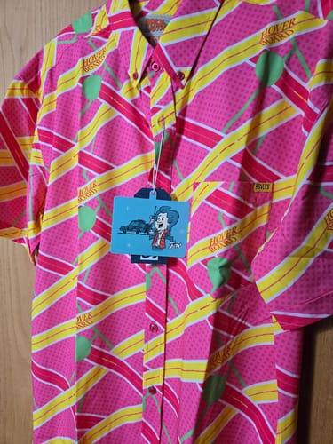 Reviewer's close-up of the bright pink and yellow 'Hoverboard Havoc' shirt with its original tag still attached.
