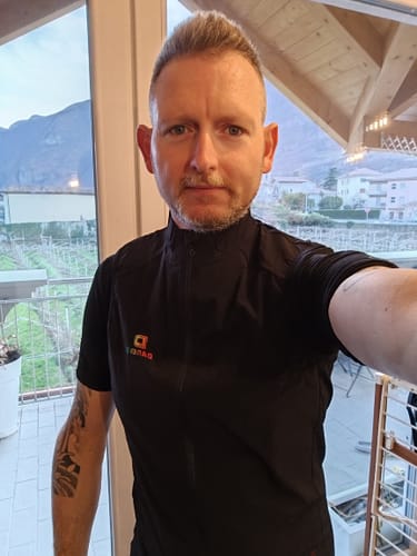 A reviewer wearing the black Honeycomb Thermal Vest indoors, showing its fit.