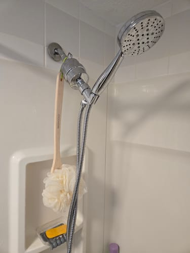 Customer's chrome Shower Head Filter and Handheld Shower Head set installed in a white tiled shower.
