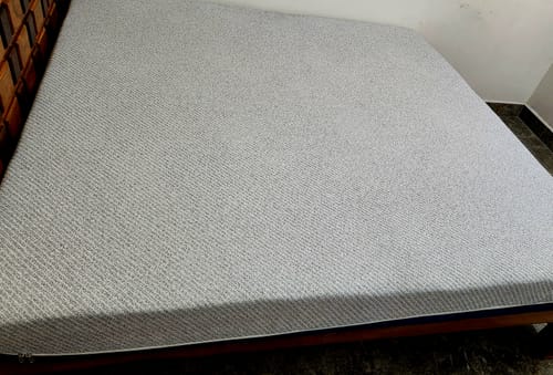 Customer's Flo Anti-Gravity™ Natural Latex Mattress with its textured grey cover, fully placed on a wooden bed frame.