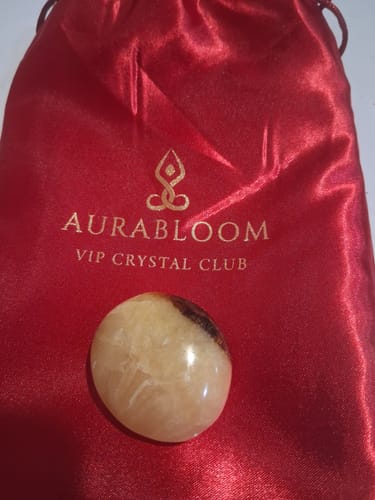 Customer's round, polished crystal from the VIP Crystal Club, shown with its red satin pouch.