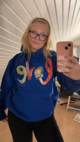 Customer taking a mirror selfie in the oversized love blue hoodie, showing the colorful front graphic.