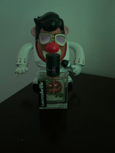 Reviewer's bottle of Cherry Pie fragrance staged in front of a fun Elvis-style Mr. Potato Head toy.