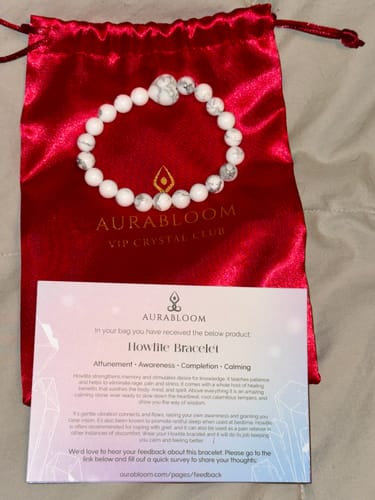 Reviewer's Howlite bracelet with marbled beads displayed on a red satin pouch next to a product info card.
