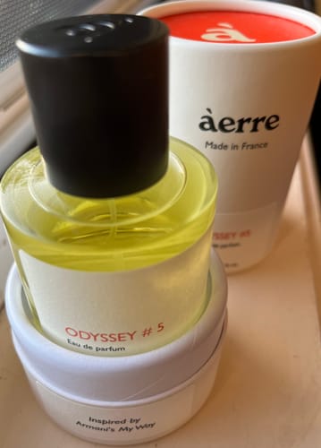 Customer's Odyssey #5 perfume bottle with its white cylindrical packaging, showing the yellow liquid inside.