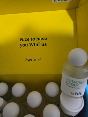 Customer's bottle of Pistachio Dream perfume inside its bright yellow packaging with other bottles.