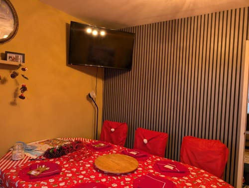 Customer's premium acoustic wall panels installed as a feature wall behind a TV in a dining room decorated for Christmas.