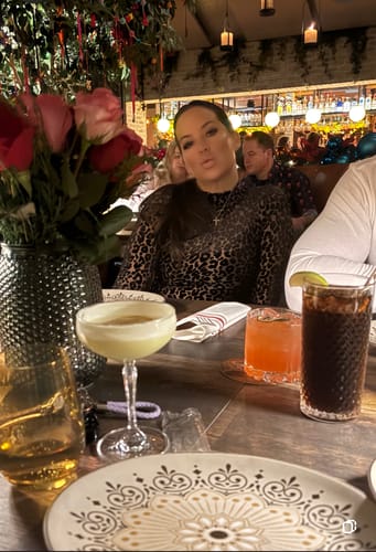 Reviewer wearing the leopard print Burnout Print Turtleneck Bodysuit while sitting at a restaurant table.