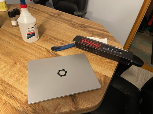 Customer shows the Barricade film box and tools next to a laptop before application.