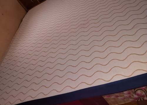 Customer's new Flo Mattress Ergo with a white wavy-patterned top and blue sides, fully expanded on a bed.