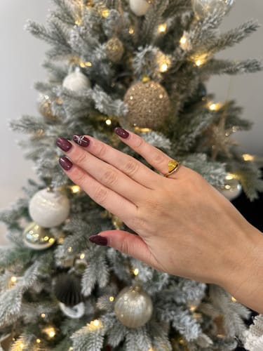 Customer wearing the gold Pia Birthstone Ring on their pinky finger with a festive Christmas tree background.
