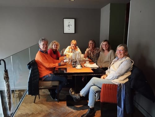 Anmelder har på seg den stilige, oransje langermede genseren ved et bord med andre.