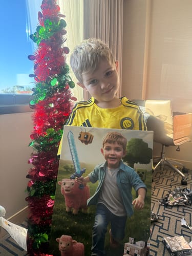 A customer's happy son holding his personalized The Minecraft Kid canvas.