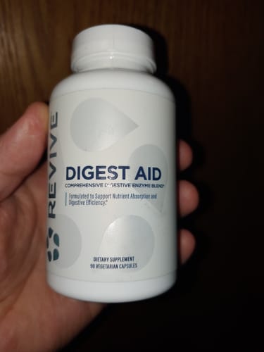 Customer holding a white bottle of Revive Digest Aid supplement in their hand.