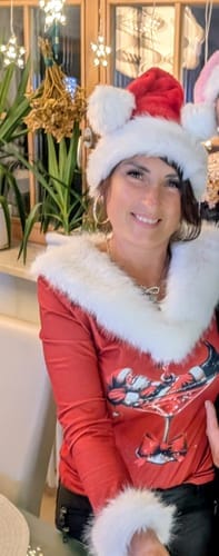 Kunde i en rød, langermet topp med juletrykk og en myk, hvit kant.