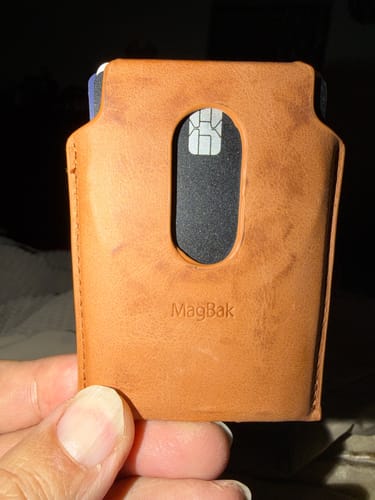 Customer holding a brown leather wallet with the black SPOTMINDERS Tracking Card PRO visible in the card slot.