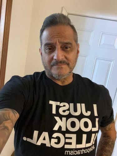 Customer wearing the black 'I Just Look Illegal Chingon OG T-Shirt'.