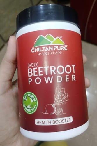 Customer holding a white jar of ChiltanPure Red Beetroot Powder, showing its red label.