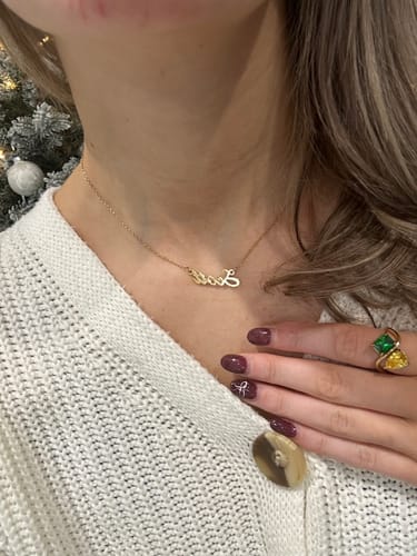 Reviewer wearing the gold Signature Name Necklace, which sits flat against their collarbone.