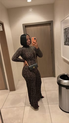 Customer posing in a restroom, wearing the form-fitting leopard print Burnout Wide-Leg Jumpsuit.