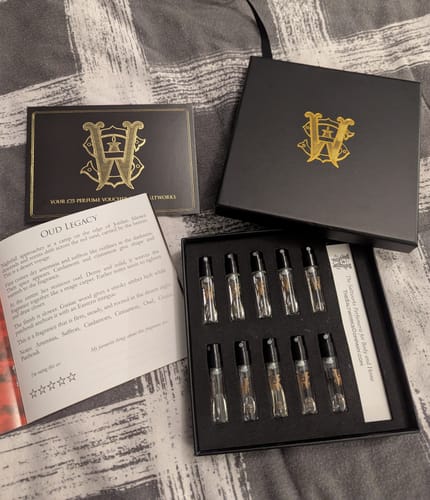 Customer's Men's Discovery Set unboxed, showing ten glass vials, the black box, a voucher, and an open illustrated booklet.