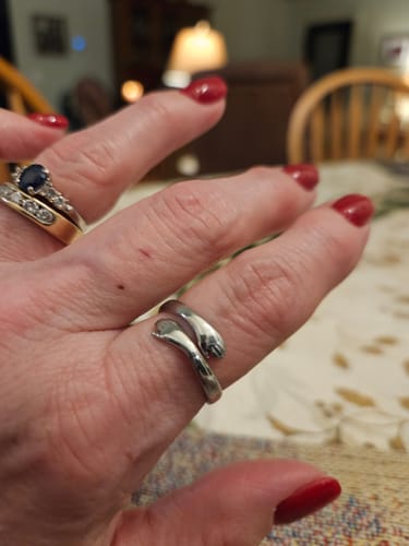 A customer wearing the silver Hug From Heaven Ring, shaped like two small arms hugging their index finger.