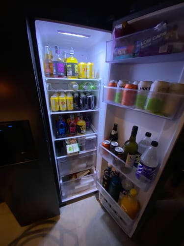 Customer's open refrigerator stocked with bottles of Blue Rasp 700ml and other drinks.