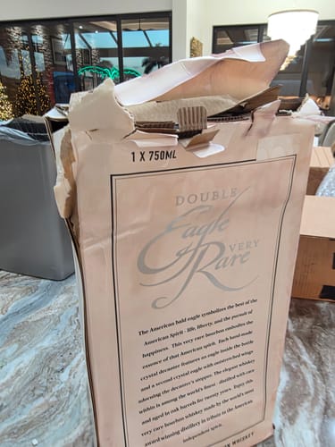 Reviewer's damaged and stained box for Double Eagle Very Rare Bourbon Whiskey, shown on a countertop.