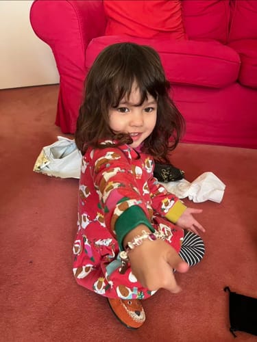A reviewer's child happily showing the 'Purple Fairy Dream' silver charm bracelet on their wrist.
