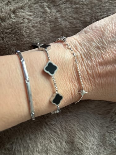 Customer's wrist wearing three assorted silver-colored bracelets against a furry surface.