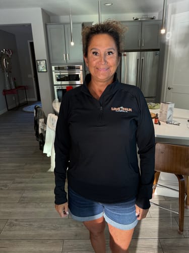 Customer wearing the black Quarter Zip Performance Pullover in a kitchen, showing the front view and fit.