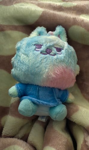 Customer's colorful and fluffy Tubatou Soobin doll with sleepy eyes, wearing a blue hoodie on a blanket.