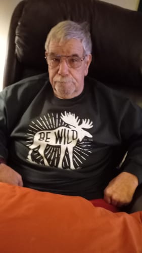 Customer sitting in a chair wearing the dark Be Wild Moose Sweatshirt.