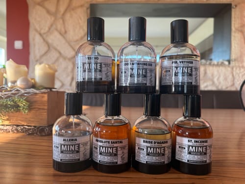 La collezione di profumi del cliente, che include ST INCENSE, disposta su un tavolo di legno.