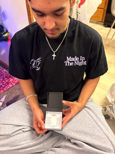 Customer wearing the Artisan Cross on Cuban Link Chain while holding the open gift set box with its message card.