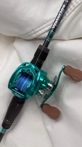 Close-up of a reviewer's Waterloo Carbon Mag rod featuring a shiny teal reel and matching rod accents.