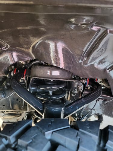 A customer's view of the black Upper Control Arm kit installed on a Dodge Ram 1500, seen inside the shiny wheel well.