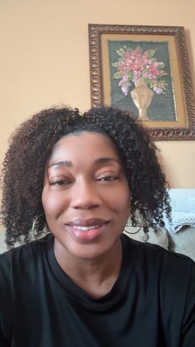 Customer smiling while showing her installed medium brown, kinky curly human crochet hair.