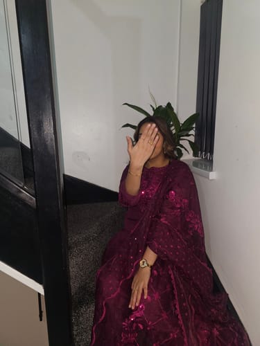 Customer sitting on stairs in a magenta outfit, holding up their hand to show the Pia Birthstone Ring.