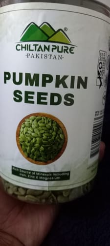 Customer holding a clear jar of Chiltan Pure Pumpkin Seeds with the label and seeds visible.